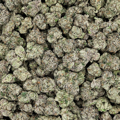 Close-up of a pile of green cannabis buds THCa Flower - Indica - 3.5g - Revelry branded packaging with owl totem design on a white background, as seen on StewartHemp.com